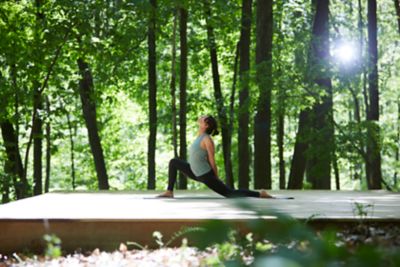 一位女士在树林里的木甲板上做瑜伽