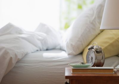 Photo of a bed with a clock on a bedstand