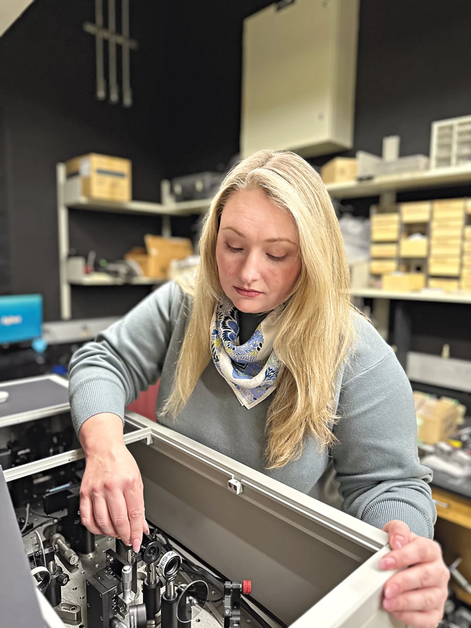 Charlotte Fuqua makes adjustments to the electronics of a femtosecond laser in her lab.