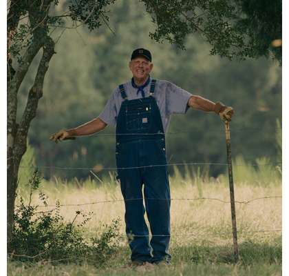 man wearing Carhartt overalls in a field