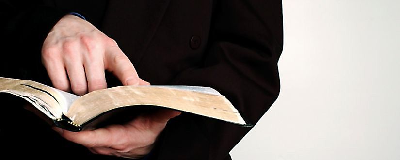 Person pointing to open Bible
