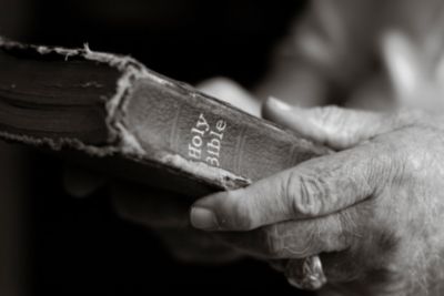 Old man's hands on a Bible.