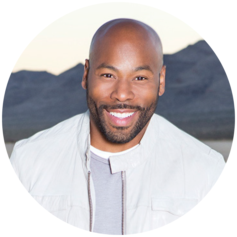 Headshot of a Anthony Evans in a white jacket, set against a mountainous backdrop