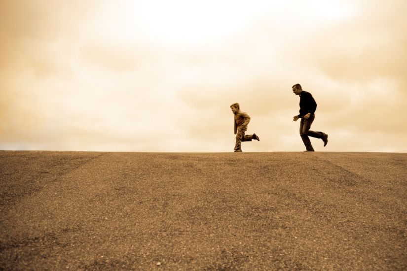 Father chasing a son through a field.