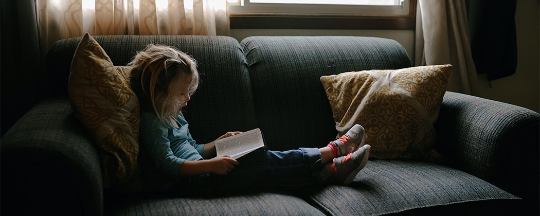 Young girl reading a Bible on couch