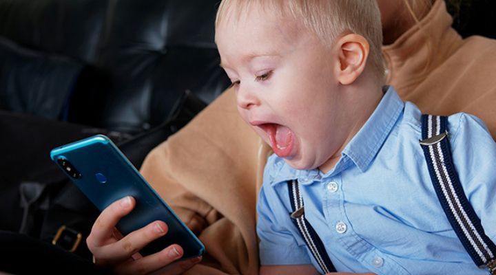 young boy smiling at phone screen