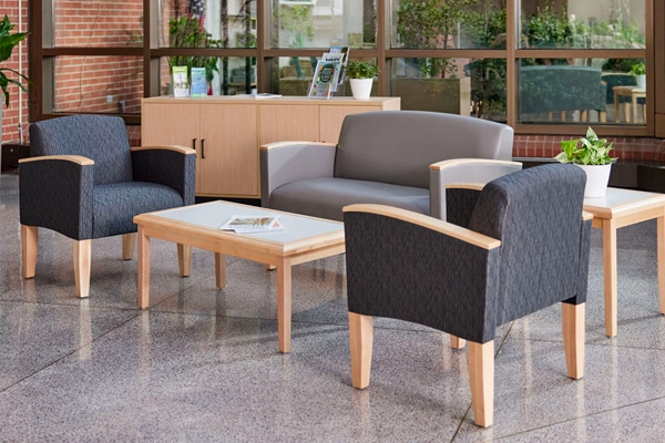 Modern reception area with USA-made Belmont Collection gray loveseat, blue armchairs and wooden tables.