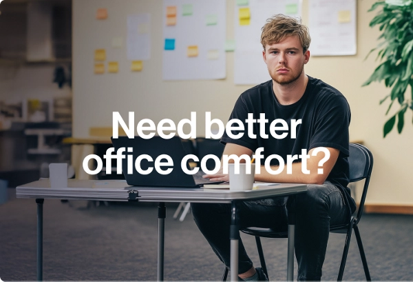 A young man in a black T-shirt sits at a foldable desk with a laptop and a coffee cup, looking at the camera. To the left, large white text reads “Need better office comfort? Let’s solve that.” A potted plant is on the right, and the background shows a bl