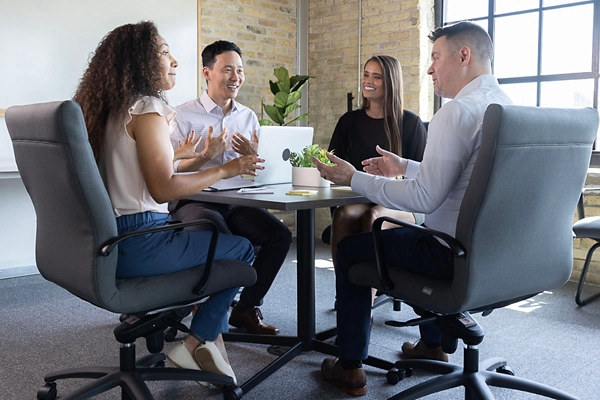 4 coworkers sitting at a round conference room table