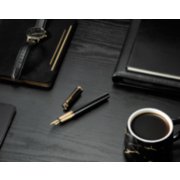 black and gold uncapped fountain pen on desk with watch, ledger, and coffee image number 8