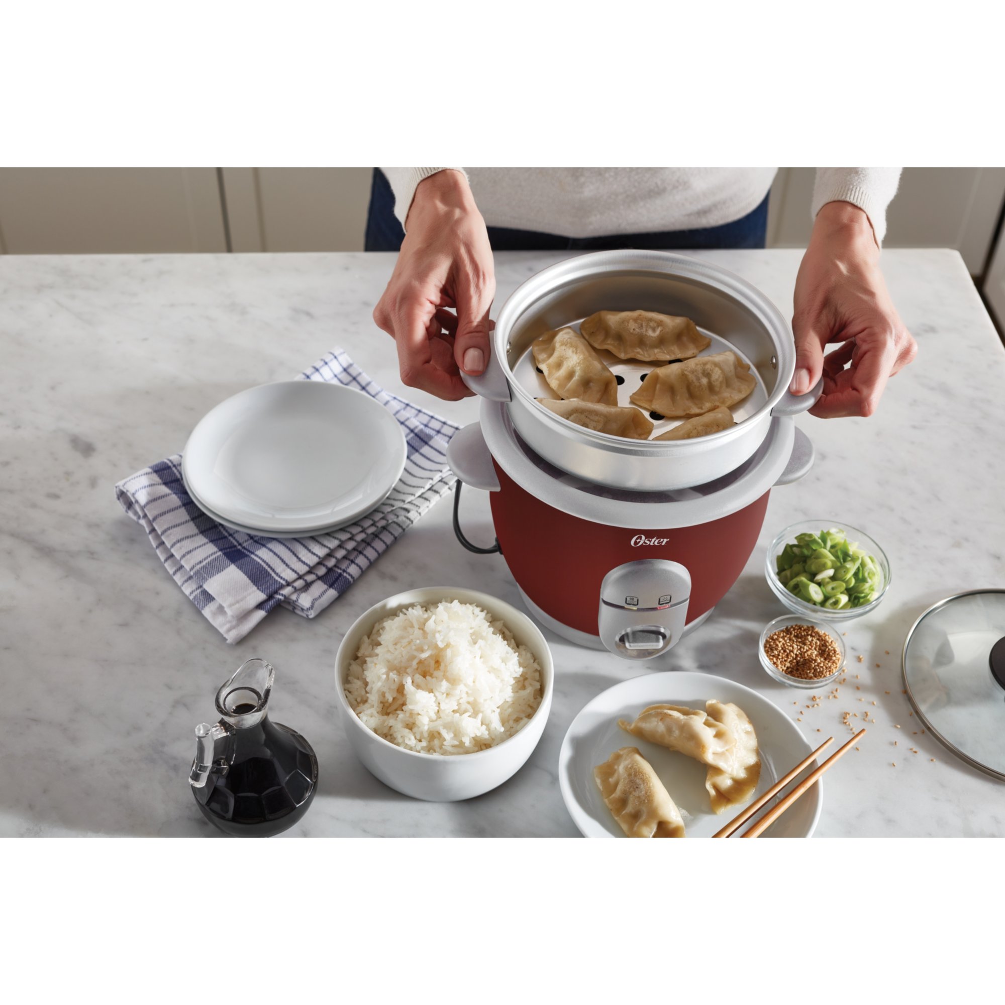 https://s7d9.scene7.com/is/image/NewellRubbermaid/4722000000-oster-rice-cooker-with-steamer-red-top-down-with-food-lifestyle-with-talent-1?wid=2000&hei=2000