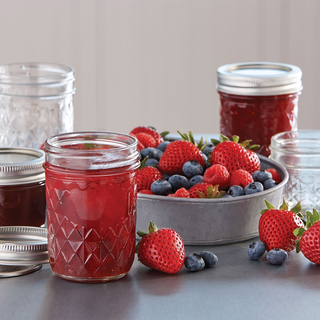 Canned jam in mason jars on table in home