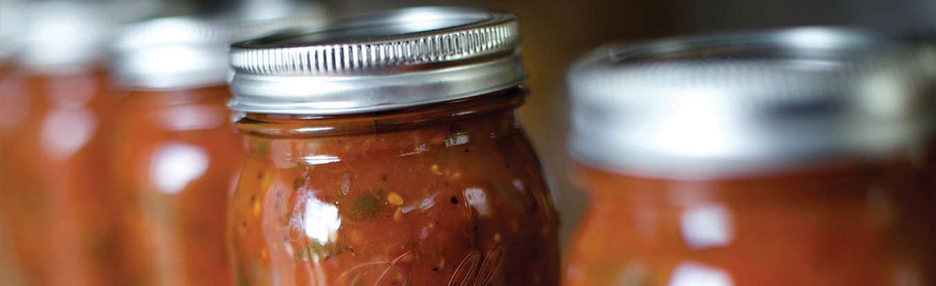 One Ball jar of tomato sauce in focus among several other jars