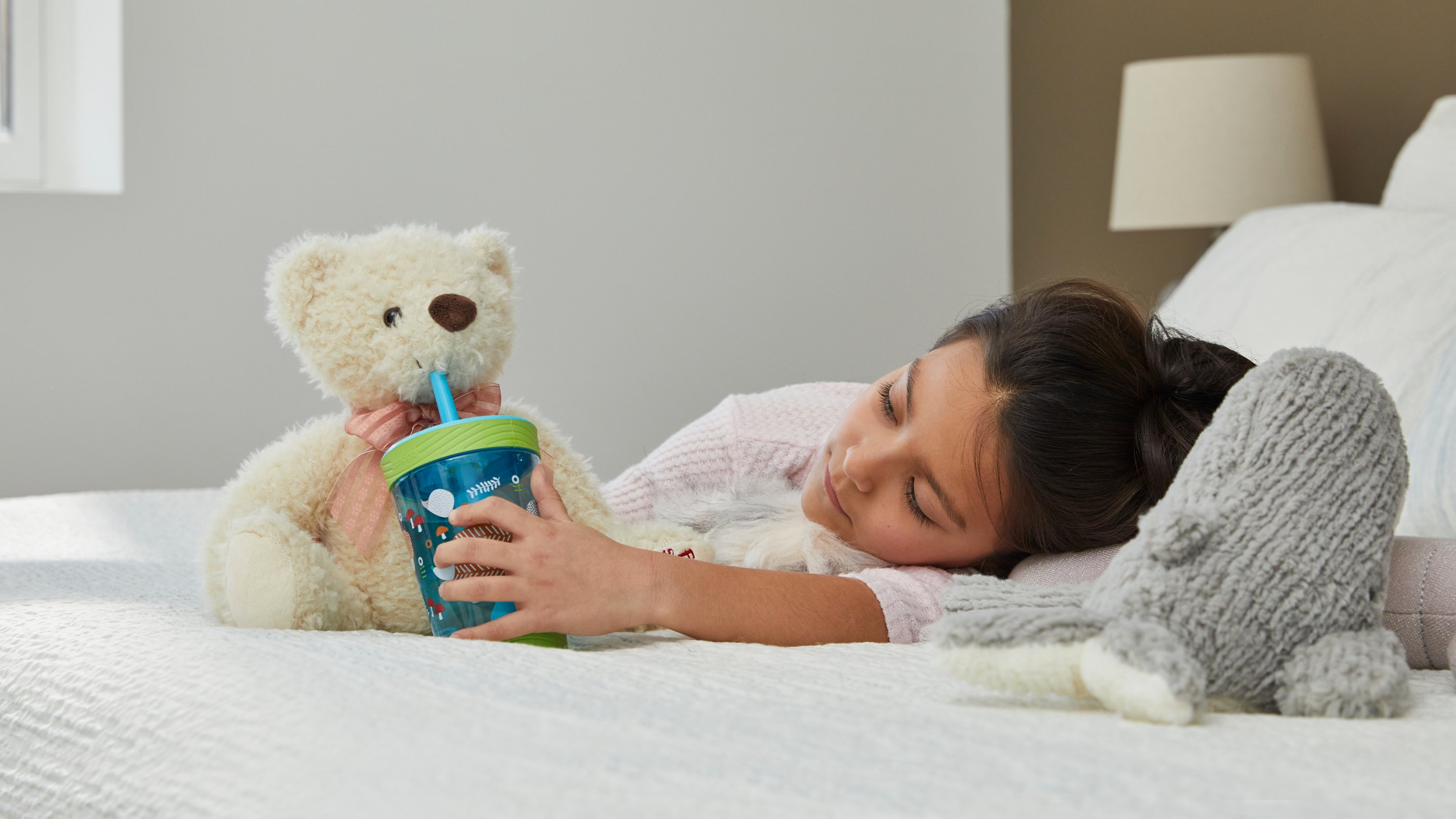 child holding kids plastic tumbler to teddy bears mouth