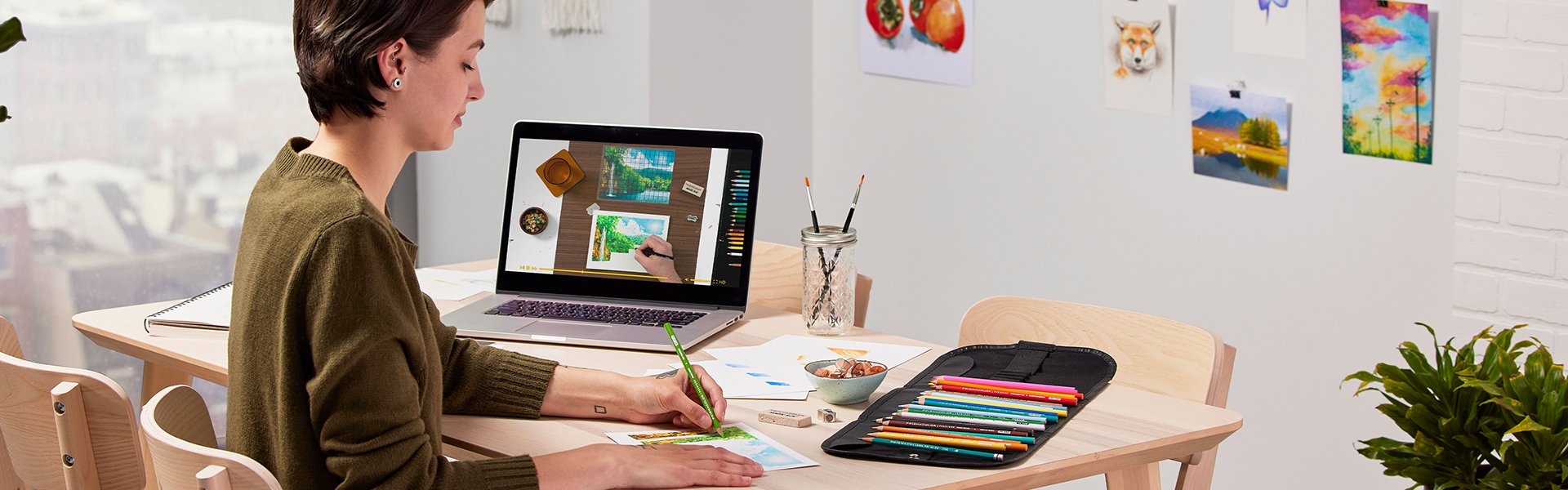 woman drawing with colored pencils with tutorial on laptop