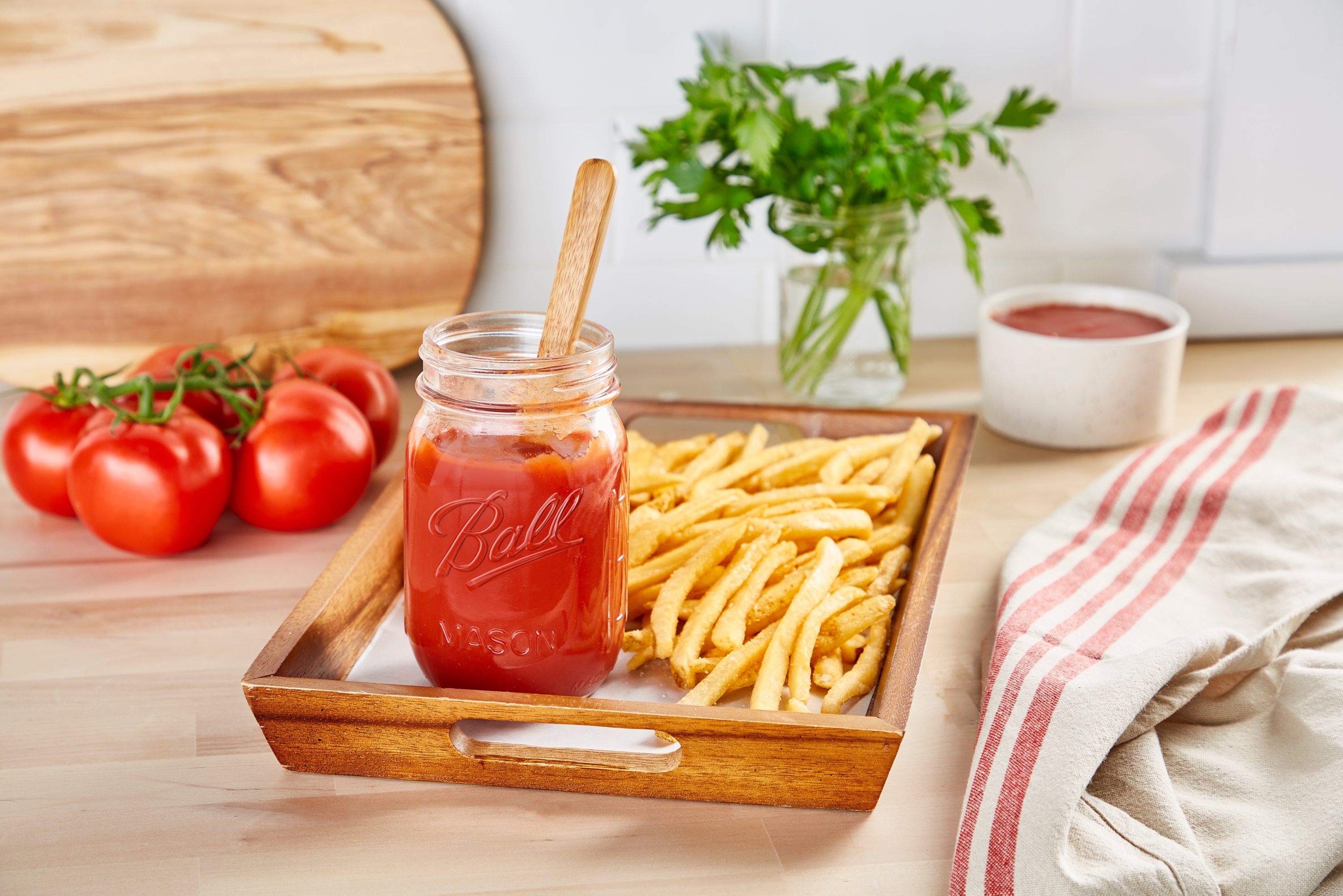 homemade tomato ketchup in a glass ball jar on a tray of fries