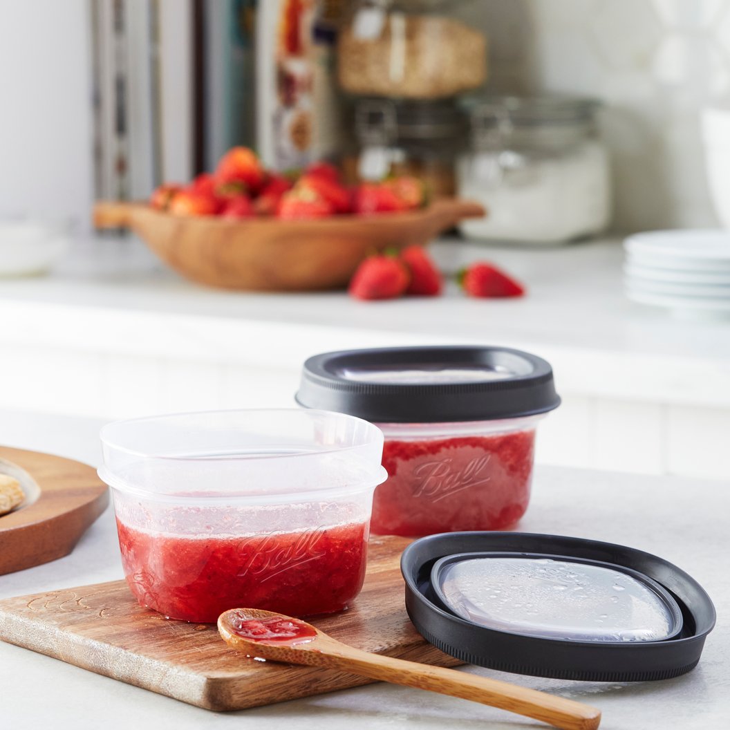 jam inside plastic containers on cutting board with wooden spoon