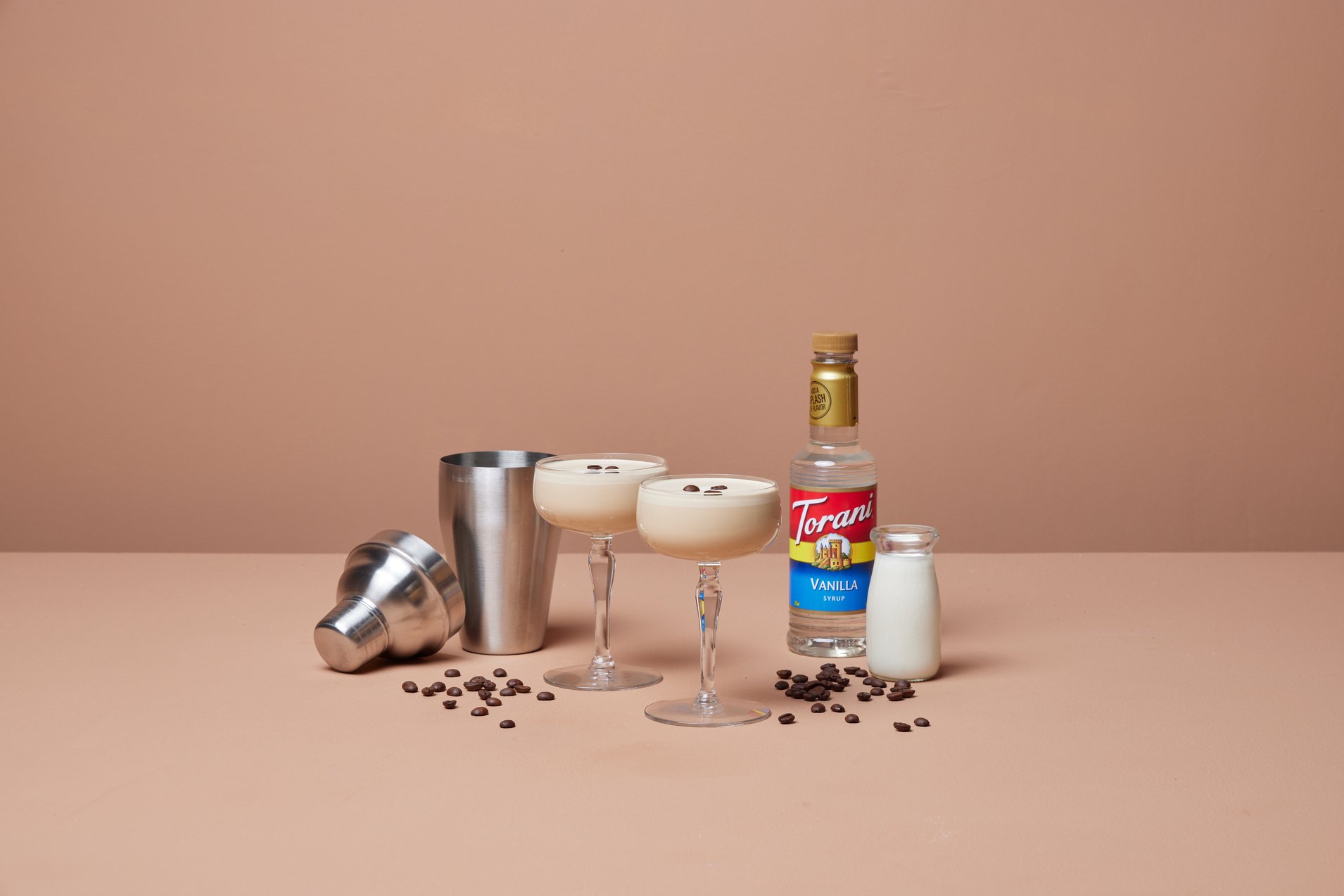 lattes in cocktail glasses with vanilla syrup and milk next to cocktail shaker