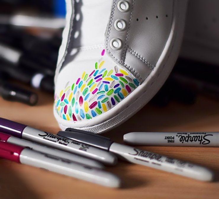 Assorted Sharpie markers next to decorated sneaker