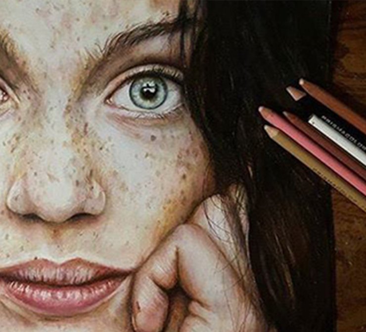 Colored pencils next to a portrait drawing