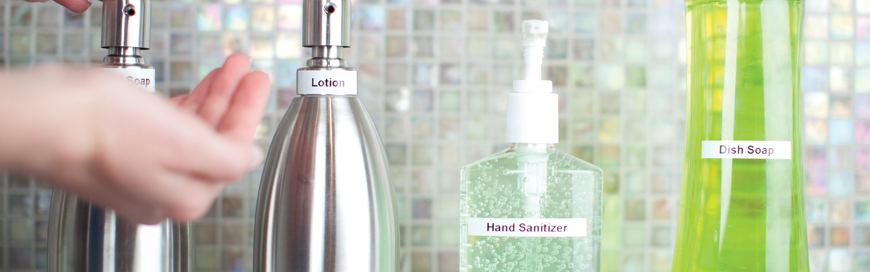 A hand pressing down on a labelled lotion dispenser.