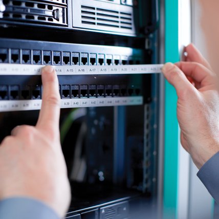 A person applying a long, white label to a telecommunications panel.