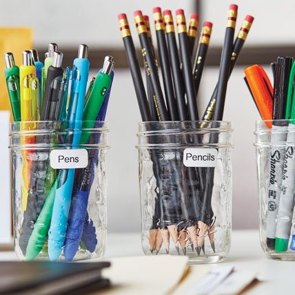 Labeled jars of pens, pencils and markers.