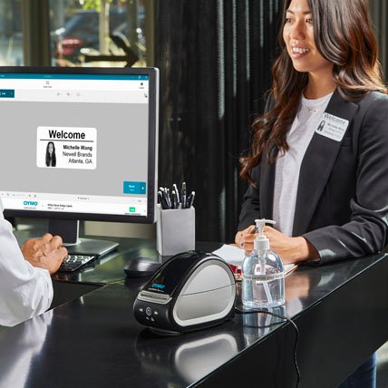 A person using a computer to create and print a welcome label for a visitor.