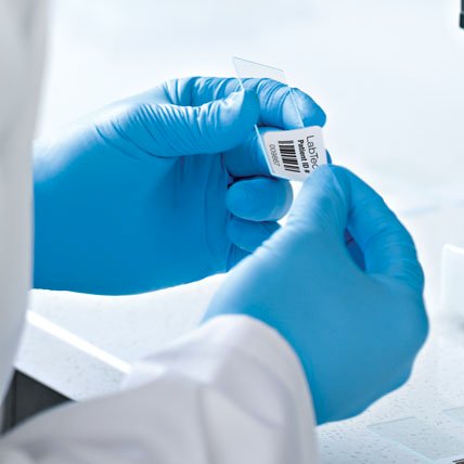 A medical professional placing a barcode label on a glass slide.