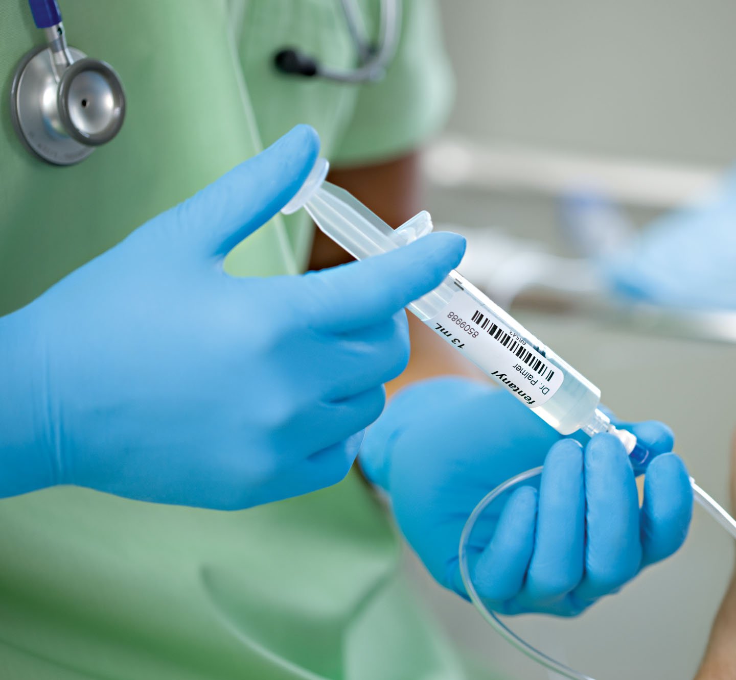 A hand pressing down on a labeled plastic injector syringe.