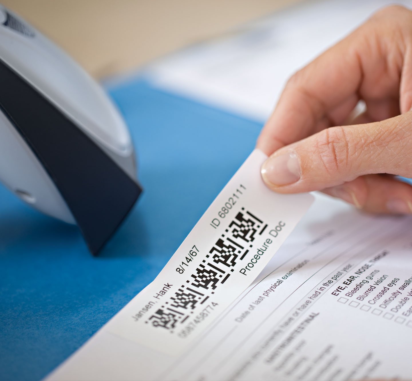 A hand applying a Q R code label to a document.