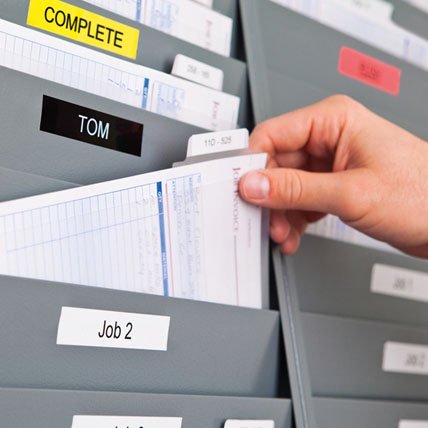 A hand placing a file into a labeled file holder.