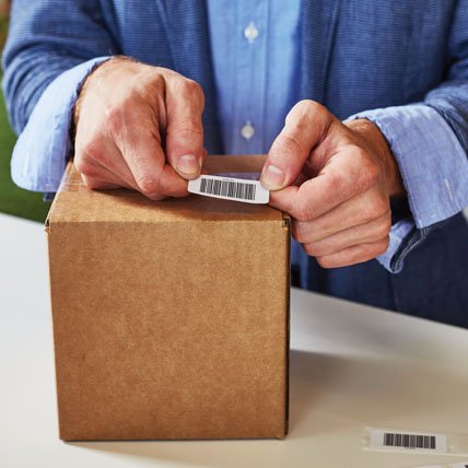 A person placing a barcode label on a package.