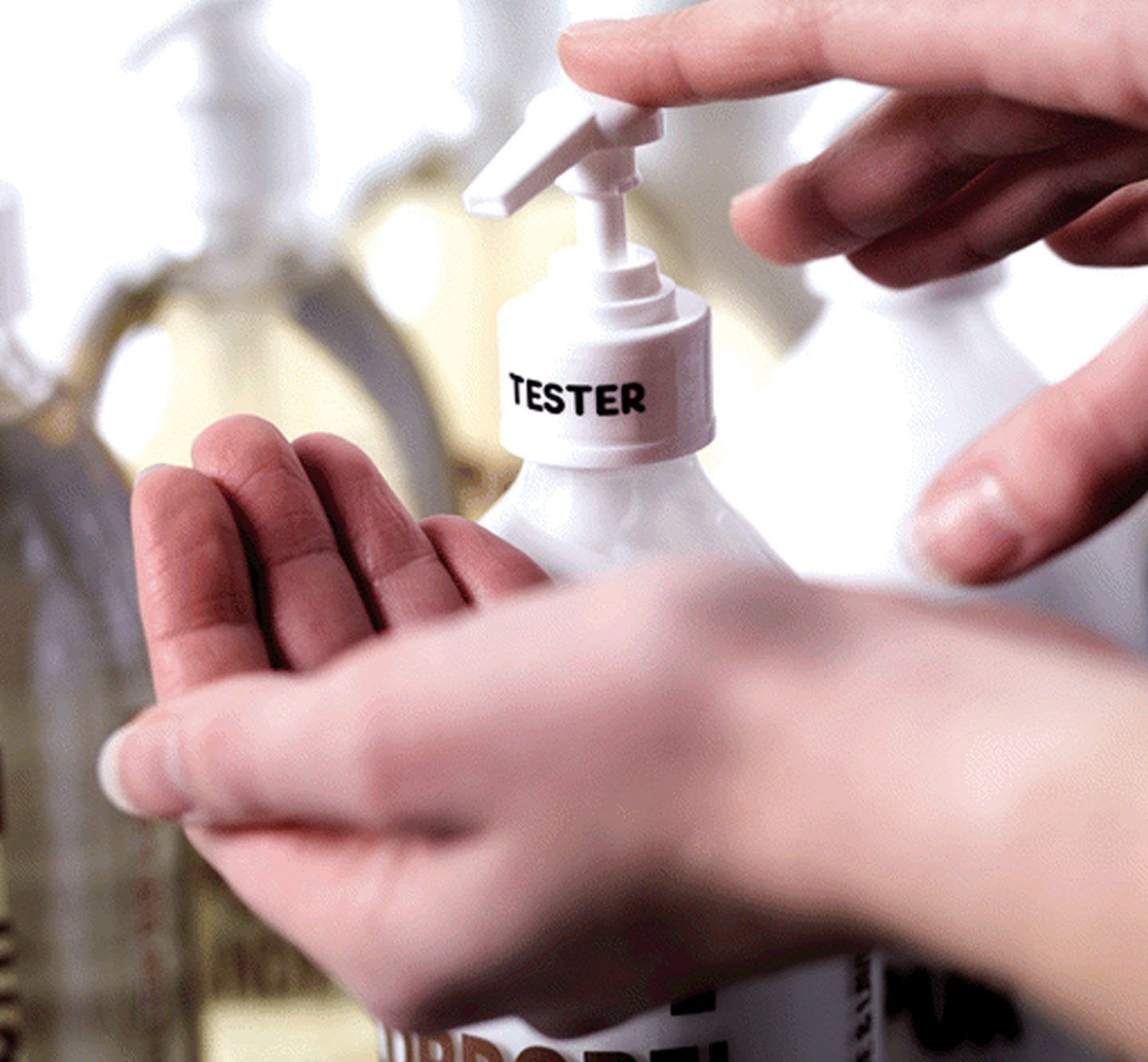 A hand pressing down on a labeled dispenser.