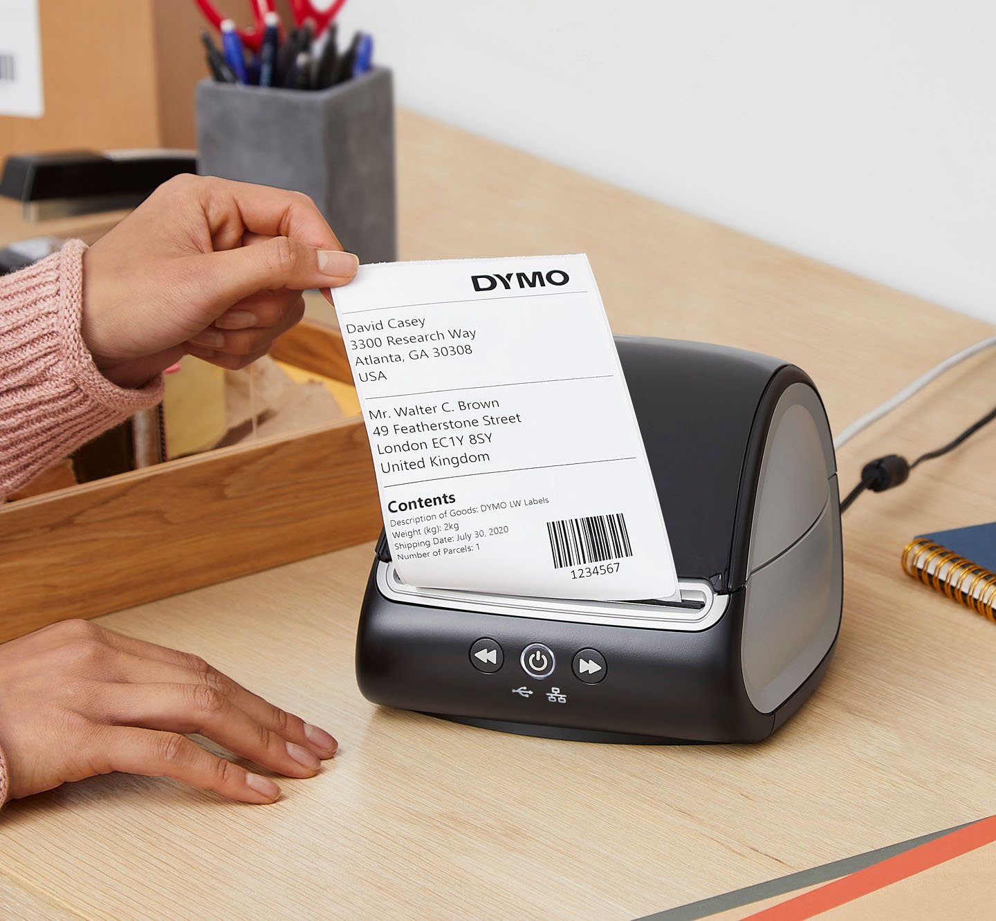 A person tearing a barcode label from a Label Writer 5 X L.