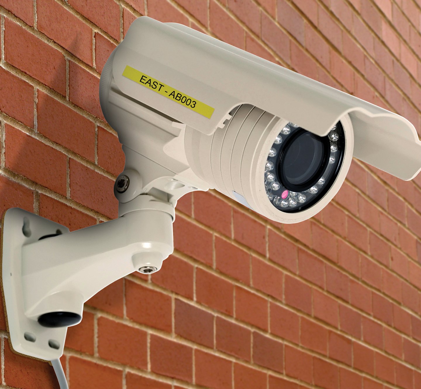 A labeled security camera mounted to a brick wall.