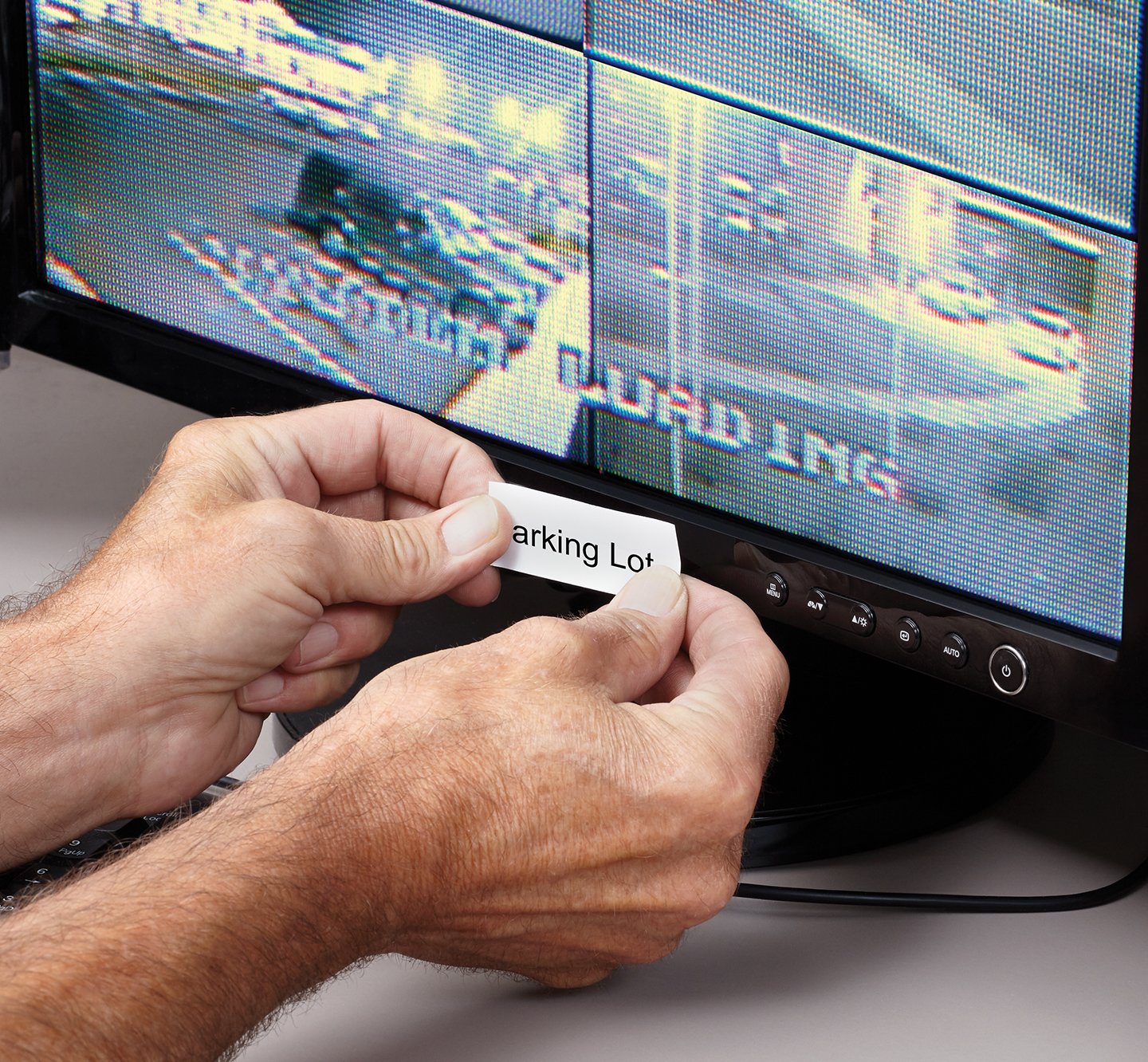 Hands placing a label onto a security monitor.