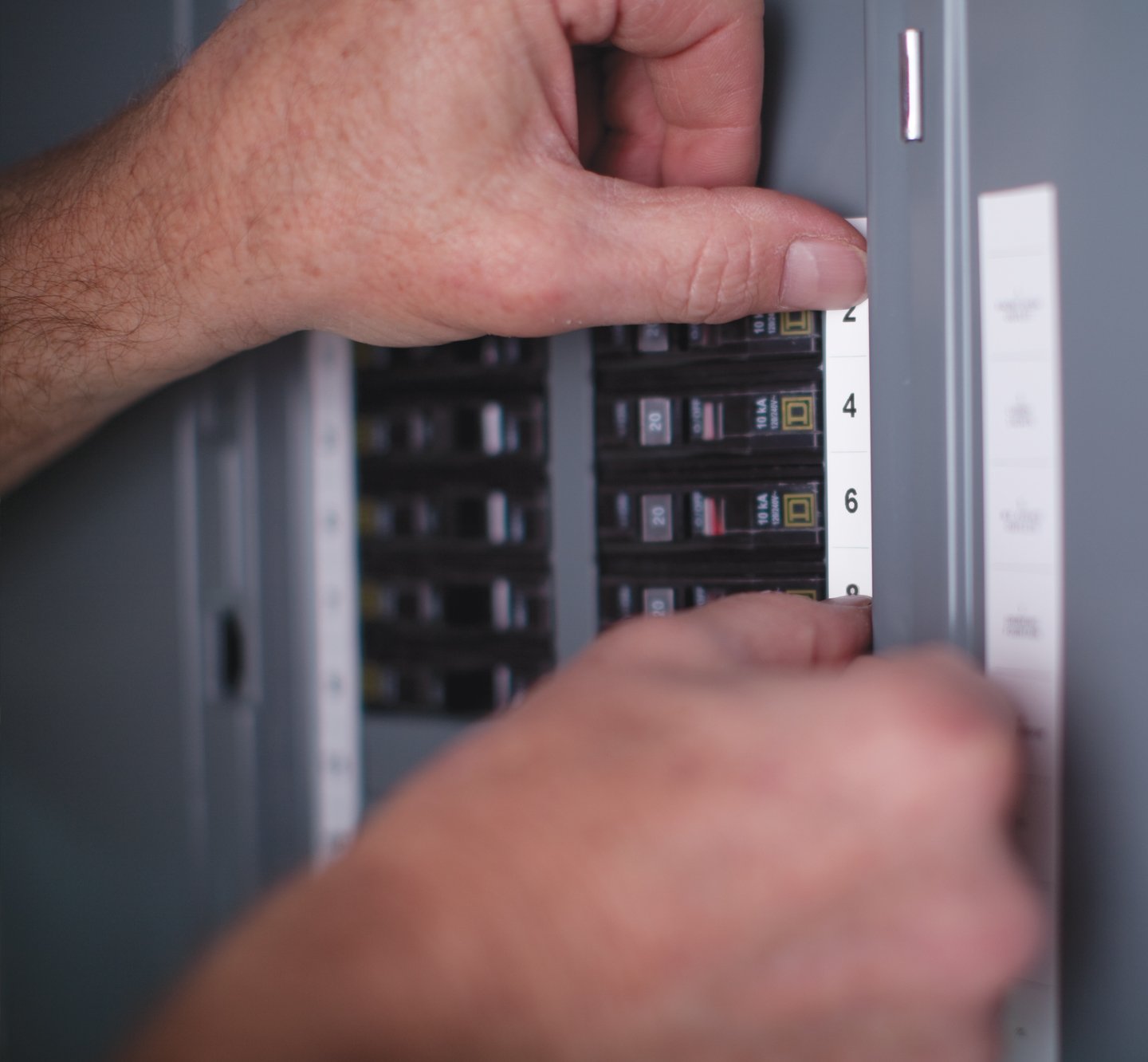 Hands placing a label onto a fuse box.