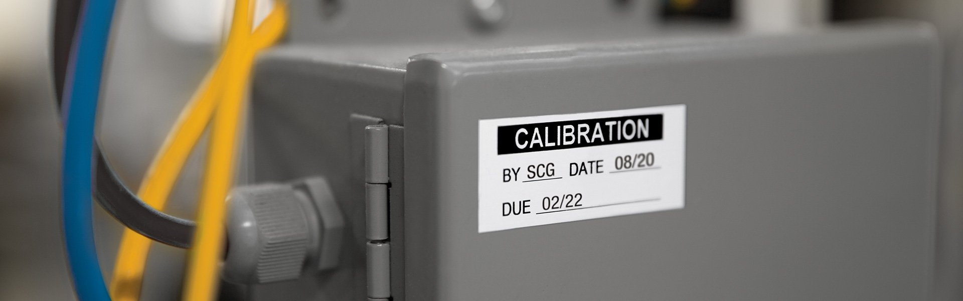 A labeled metal electrical box that reads calibration and due date.