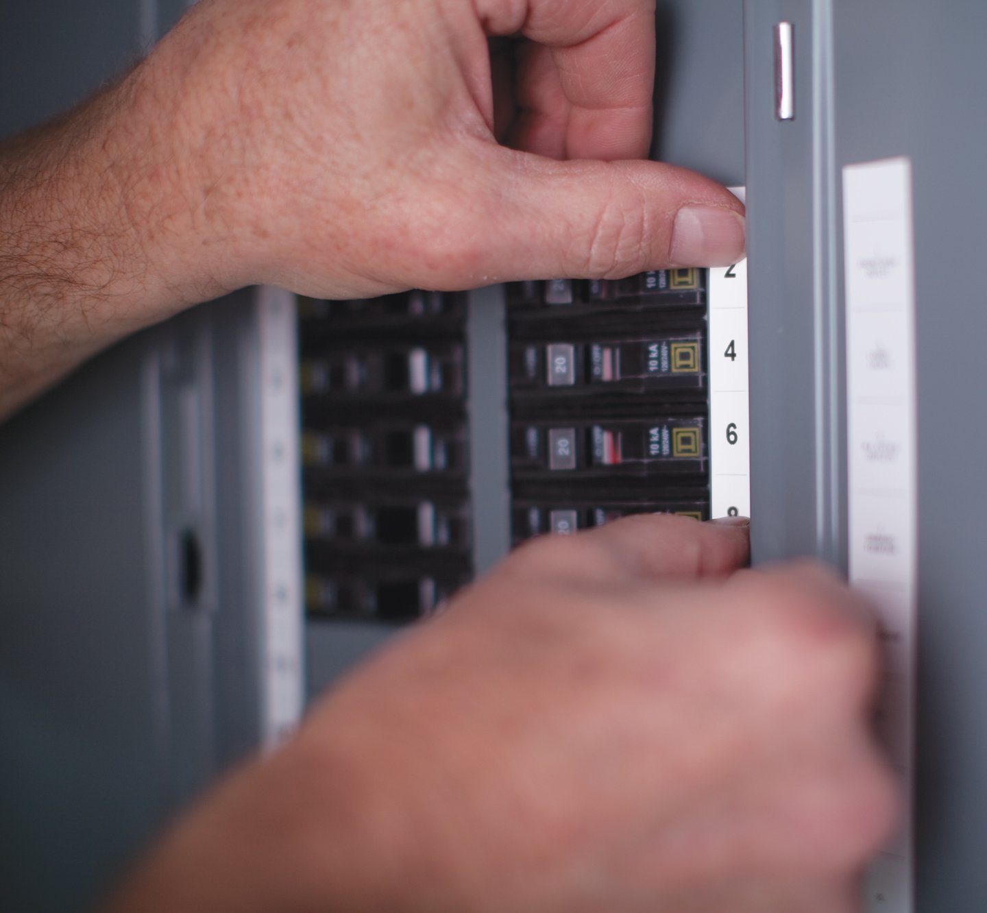 Hands placing a label on a fuse box.