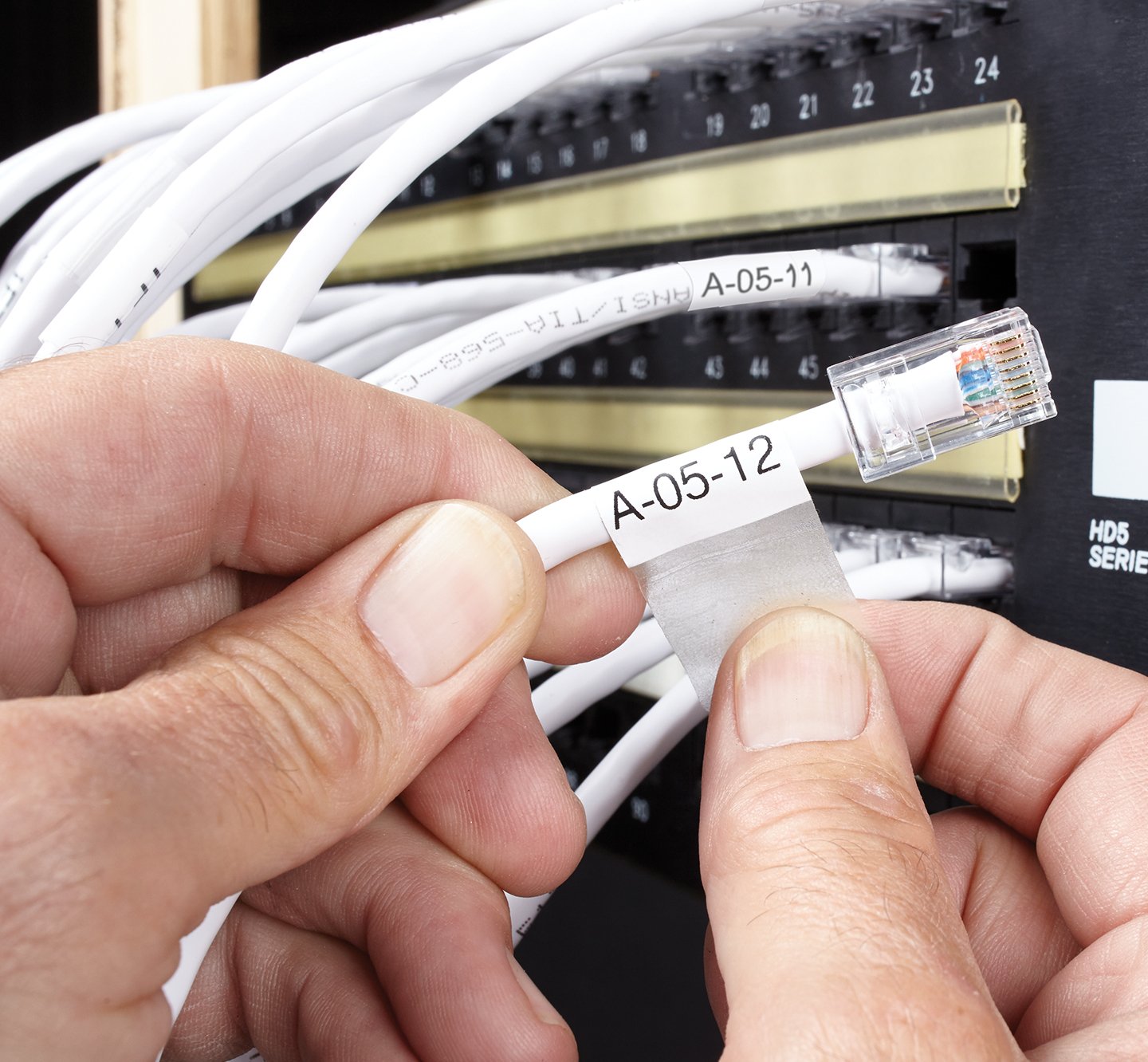 Hands placing a cable wrap label onto a modem cable.