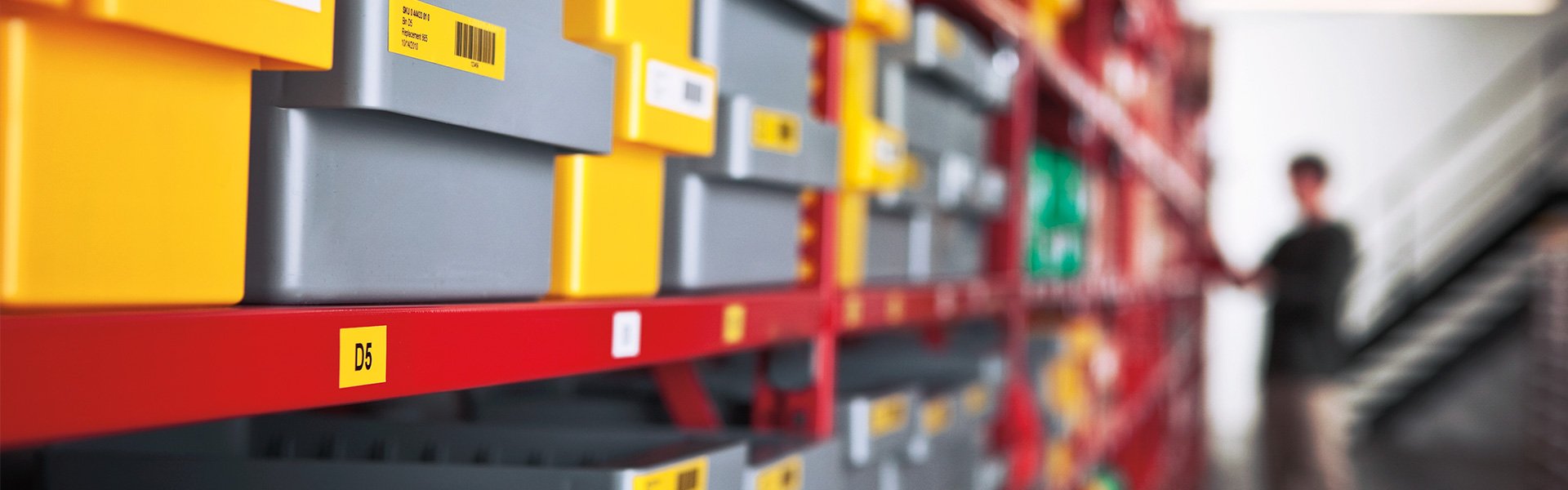 Rows of plastic bins with white and yellow barcode labels.