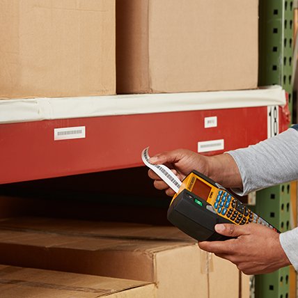 A person using a Rhino 6000 plus label maker to print a long barcode label.