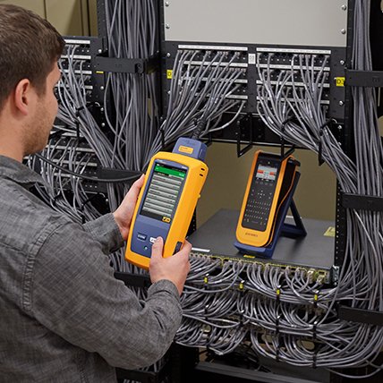 A man using an X T L label maker to create a label for an electronic wiring panel.