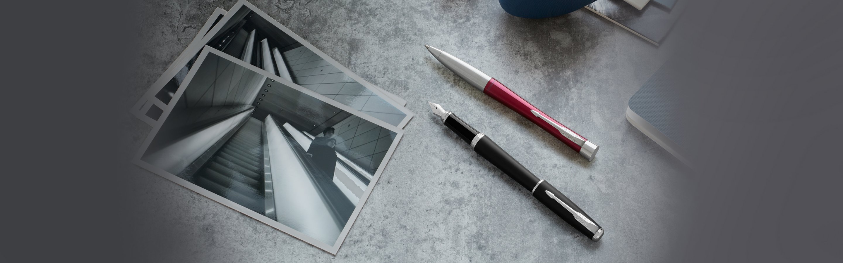 An Urban ballpoint pen with chrome trim laid on a desk near a folded pair of glasses.