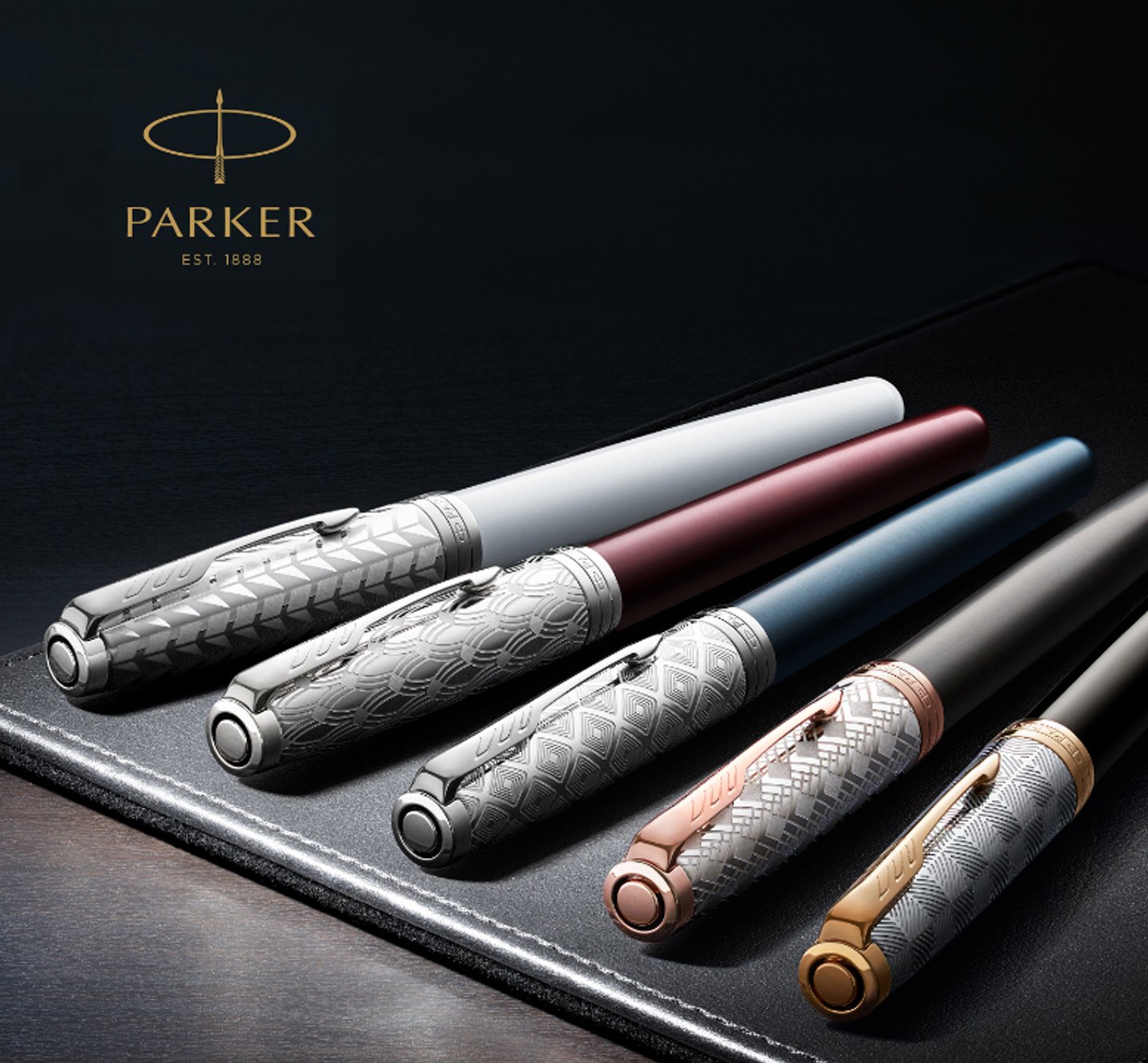 Five capped pens in various colors laid on a leather mat.
