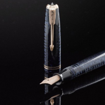 A Vacumatic fountain pen laid on its side with pen cap stood upright.
