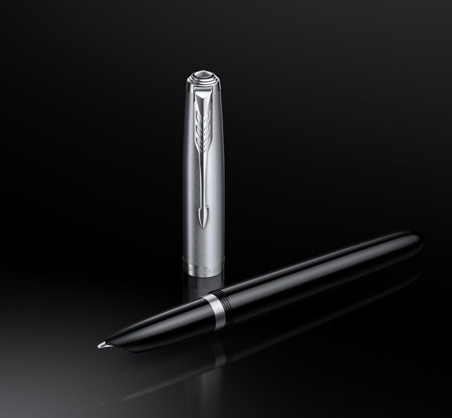 An uncapped Parker 51 pen laid down with pen cap stood upright.