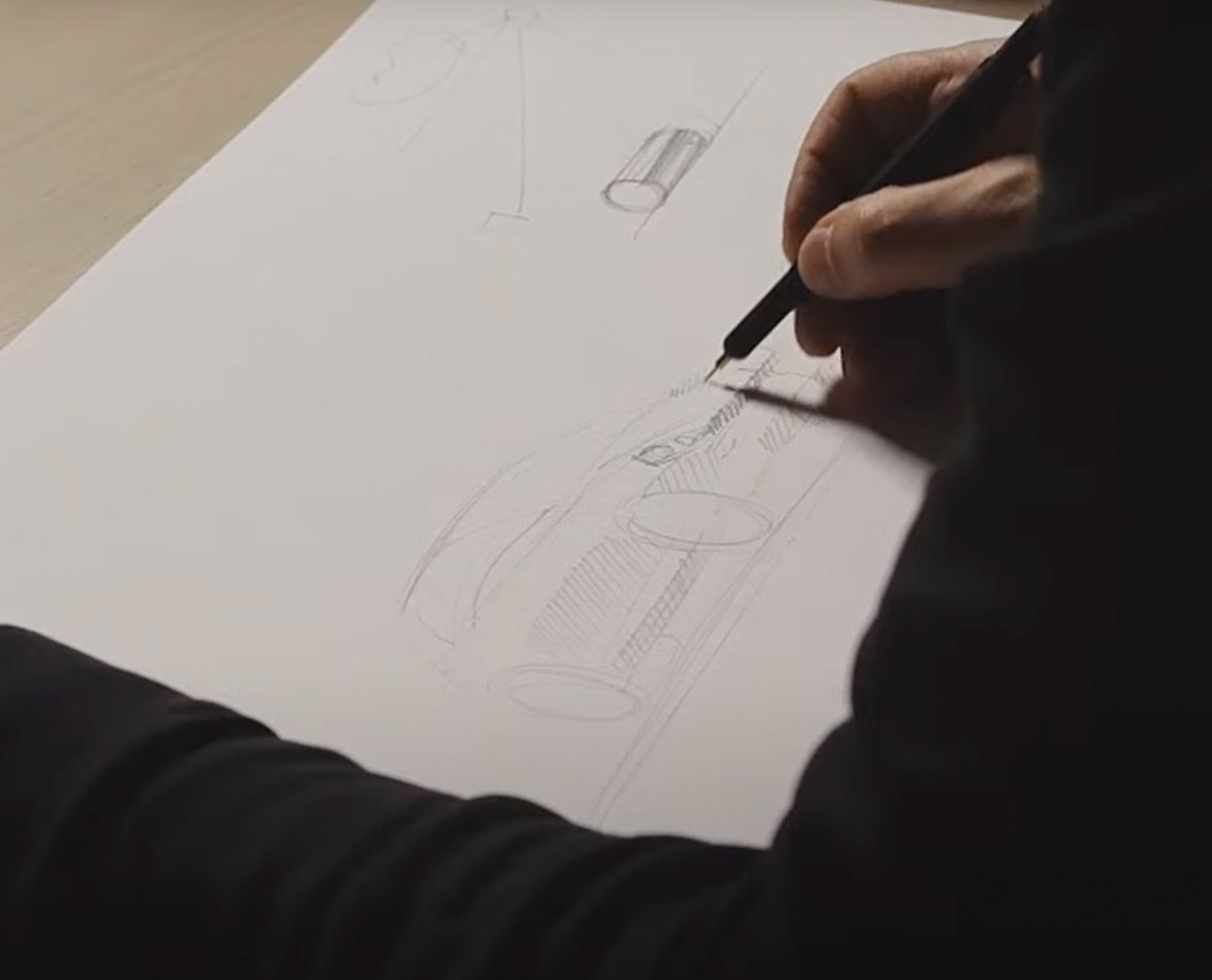 Closeup of a hand sketching a car with a mechanical pencil.
