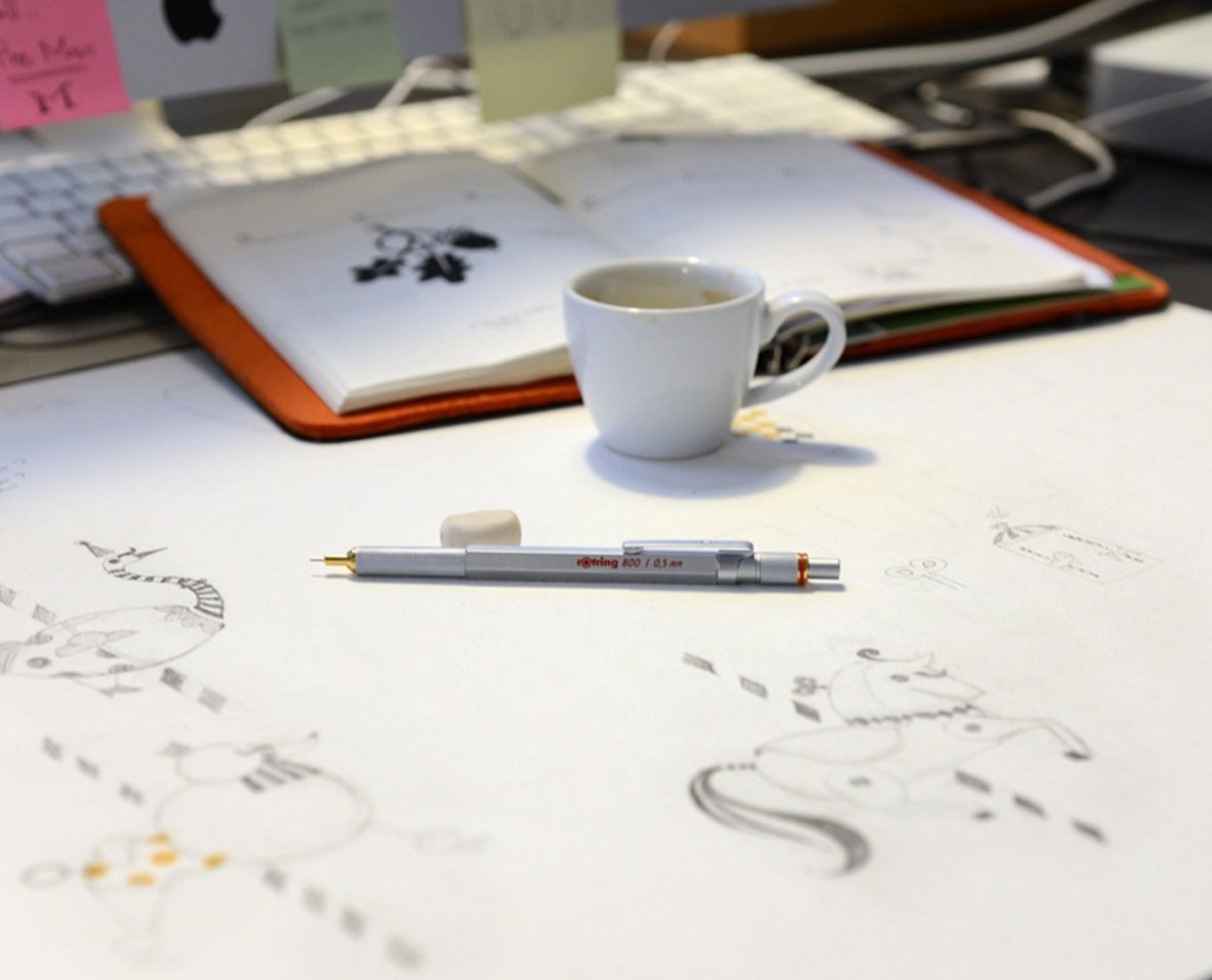 An 800 mechanical pencil next to an espresso cup laid over paper with doodles on it